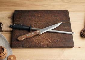 viejo cuchillo afilado y afilador con mango sobre un fondo de madera foto