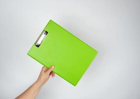female hand holding a green tablet for clamping papers photo