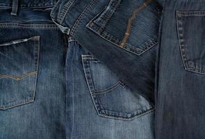 muchos jeans clásicos azules apilados caóticamente foto