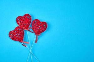 three red carved hearts on a stick on a blue background photo