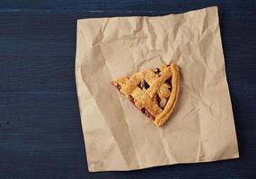 triangular slice of baked cranberry pie on brown paper photo