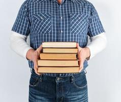 hombre con camisa a cuadros azul sosteniendo una pila de libros foto