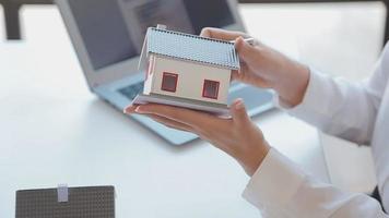corretor de imóveis entrega uma amostra de uma casa modelo ao cliente, contrato de empréstimo hipotecário fazendo aluguel e comprando uma casa e contratando o conceito de seguro residencial video