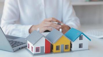 corretor de imóveis entrega uma amostra de uma casa modelo ao cliente, contrato de empréstimo hipotecário fazendo aluguel e comprando uma casa e contratando o conceito de seguro residencial video