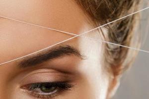 Eyebrow threading - epilation procedure for brow shape correction photo