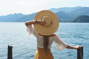 Woman is wearing straw hat looking on the beautiful lake photo