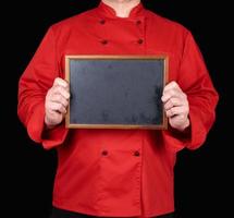 chef con uniforme rojo sosteniendo un marco de madera vacío foto