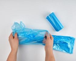 blue plastic garbage bag in hands on a white background photo