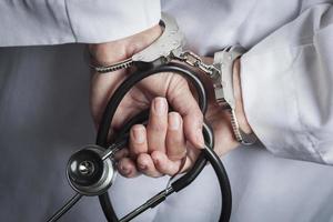 Female Doctor or Nurse In Handcuffs Holding Stethoscope photo