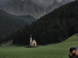 photographer taking picture of ranui church in south tyrol funes valley dolomites italy photo