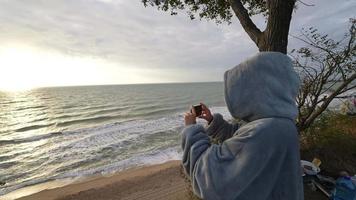 mulher fica na praia tirando foto ou vídeo com telefone video