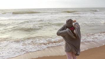 mujer en la playa fría usa el teléfono para tomar una selfie video