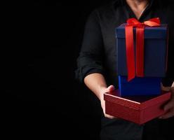 adult man in a black shirt holds in his hands a stack of paper-wrapped gifts photo