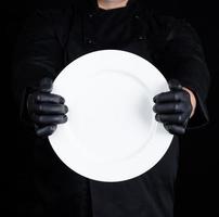 chef con uniforme negro sosteniendo un plato redondo vacío foto