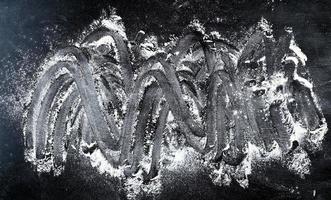harina de trigo blanca esparcida sobre un fondo negro, el producto se extiende sobre la superficie foto
