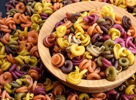 multicolored spiral raw pasta fusilli in a wooden bowl photo