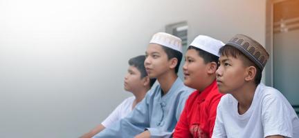niños musulmanes o islámicos asiáticos sentados con niños musulmanes en fila para orar o hacer la actividad religiosa, enfoque suave y selectivo. foto
