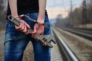 la chica esposada con la llave ajustable en el ferrocarril foto