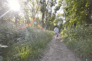 A young guy in a gray sports suit runs along the path among the photo