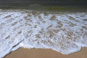 olas en la orilla de una hermosa playa tropical de arena en un día soleado foto