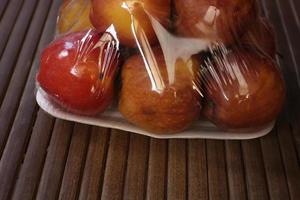 black peel with six apples wrapped in transparent plastic isolated on brown background photo