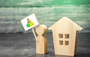 un hombre con un cartel en la casa. venta de casa. el tasador tasa la propiedad. compra de vivienda, invertir en bienes raíces. términos y condiciones favorables, baja tasa de interés. alquiler foto