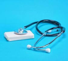 medical stethoscope and empty paper business cards on a blue background photo