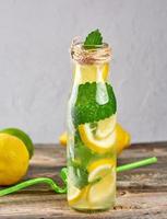 summer refreshing drink lemonade with lemons, mint leaves, lime in a glass bottle photo