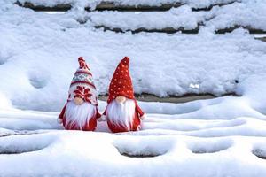 Christmas holiday card Cute scandinavian gnomes with red hat and white beard on snowy winter bench Fairytale snowfall Wintertime Hello December, January, February concept Happy New Year, Christmas photo