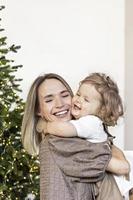 A young woman with blond hair and a little daughter against the backdrop of Christmas decorations. New year concept photo