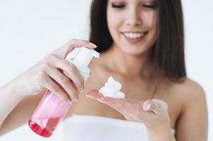 Close up portrait of young asian woman with cosmetic foam for washing in hands on white background photo