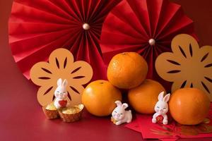 Chinese New Year of the rabbit festival concept. Mandarin orange, red envelopes, rabbit and gold ingot with red paper fans. Traditional holiday lunar New Year. Chinese character cai meaning money. photo