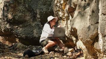 mujer geóloga que usa computadora portátil examinando la naturaleza, analizando rocas o guijarros. los investigadores recolectan muestras de materiales biológicos. Investigación ambiental y ecológica. video