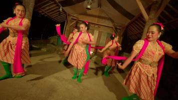 Balinese people dance together while the ritual ceremony begins in a yellow dress and green scarf inside the village video