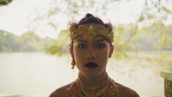 Balinese man sitting peacefully while meditating in a golden crown and golden costume inside the jungle video