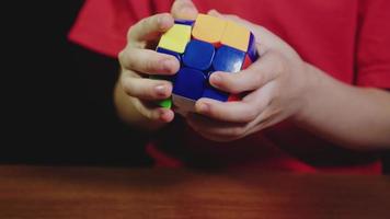 les mains du garçon résolvent le puzzle du cube de rubik