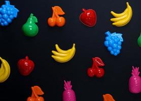 multicolored plastic toys fruits on a black background photo