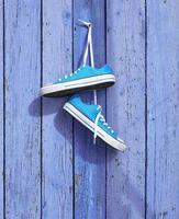 pair of blue textile sneakers hanging on a nail photo