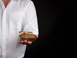 man in a white shirt holds in his left hand a little golden box photo