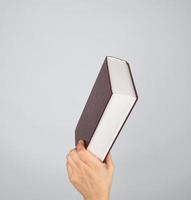 hand holds a closed book in hardcover photo