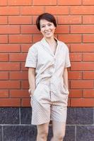 Cheerful woman in home wear pajama outdoor brick wall background emotions - sleepwear and homewear concept photo
