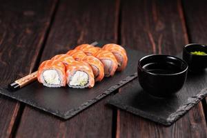 Sushi roll philadelphia with salmon and cucumber and cream cheese on black background. Sushi menu. Japanese food concept photo