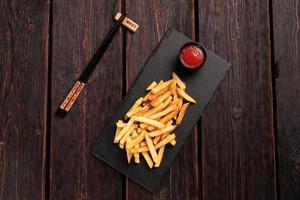 French fries with ketchup on dark wooden background top view - fast food and unhealthy eat concept photo