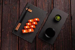 Sushi roll with tuna, onion in batter and tobiko caviar served on black board top view - Japanese food photo