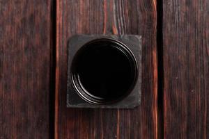 Bowl with soy sauce on wooden table, top view photo