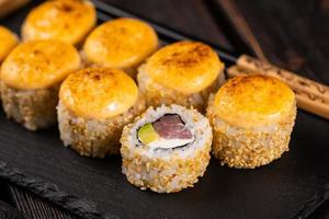 Sushi roll with tuna, avocado and tobiko caviar served on black board close-up - Japanese asian food photo