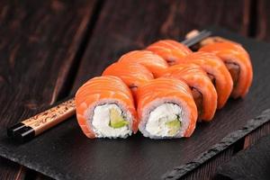 Sushi roll philadelphia with salmon and cucumber and cream cheese on black background. Sushi menu. Japanese food concept photo