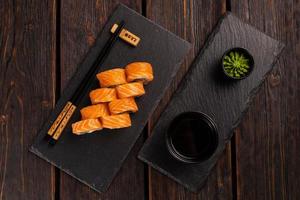 Sushi roll philadelphia with salmon and cucumber and cream cheese on black background. Sushi menu. Japanese food concept top view photo