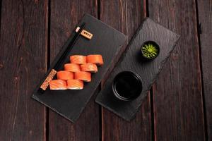 Sushi roll philadelphia with salmon and cucumber and cream cheese on black background. Sushi menu. Japanese food concept top view photo