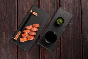 Sushi roll philadelphia with salmon and avocado and cream cheese, caviar on black background top view. Sushi menu. Japanese food concept photo
